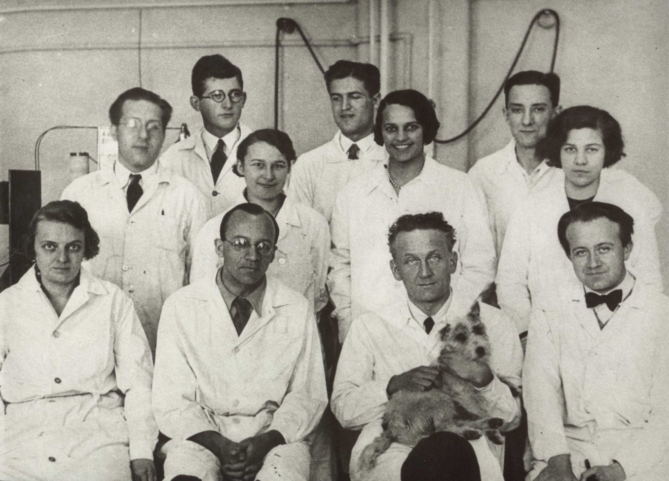 Szent-Györgyi Albert szegedi munkatársai körében, 1933-ban (kutyával az ölében). Mellette balról Gözsy Béla, mögötte a felesége, Demény Kornélia