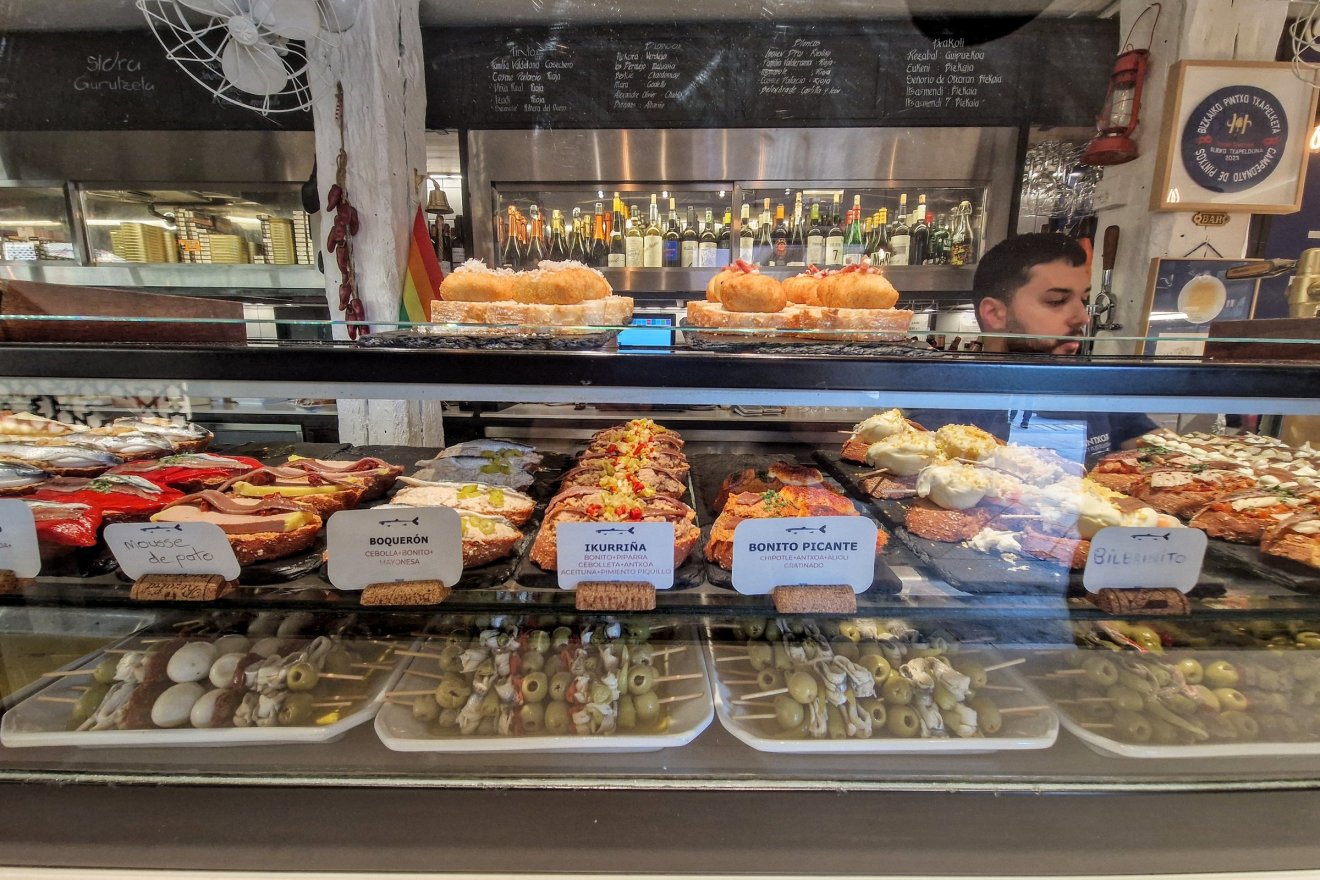 Pintxosbár Bilbaóban. Az etikett szerint előre italt, lehetőleg egy pohár rioját kérjünk a pultostól a ház ajánlatából, amiből aztán két harapás közben vagy akár sűrűbben is kortyolgathatunk, a végén az üresen maradt fogpiszkálók alapján fizetünk, és már telepedhetünk is át a szomszéd lokálba