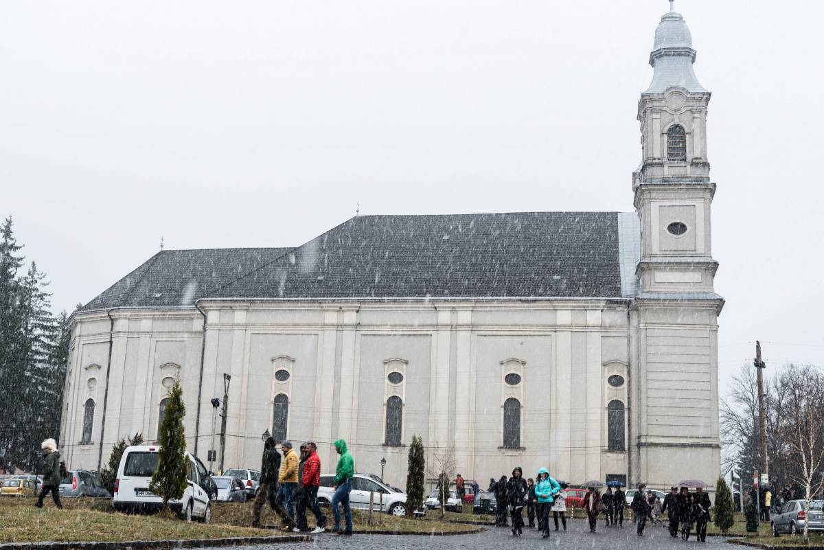 Mise után távozók havazásban a csíksomlyói kegytemplomnál a nyári időszámítás első napján •  Fotó: MTI/Veres Nándor