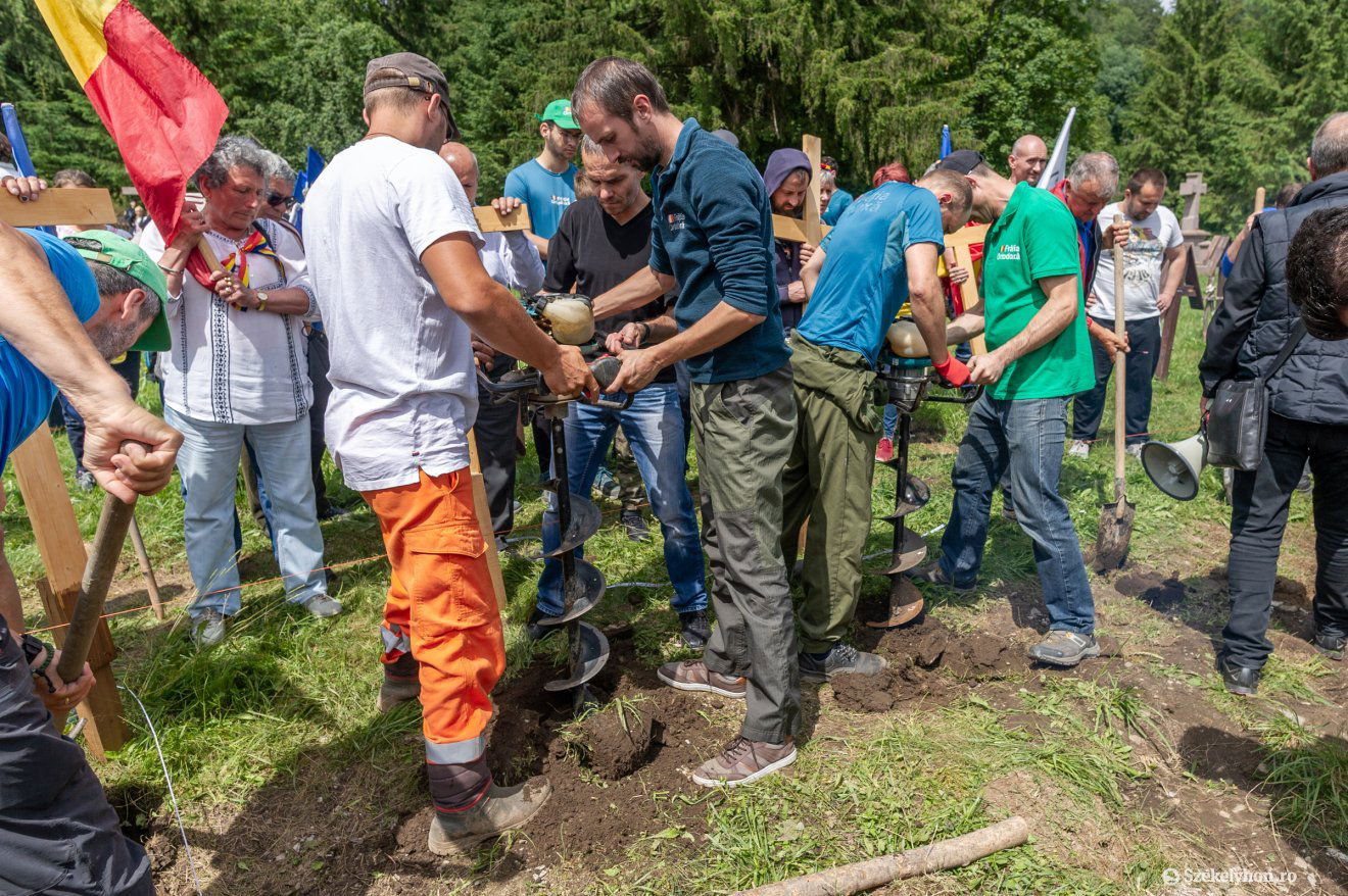 Kemény munka zajlik a haditemetőben. Szó szerint: egy autóból kihangosítva szólnak a román hazafias énekek •  Fotó: Pinti Attila