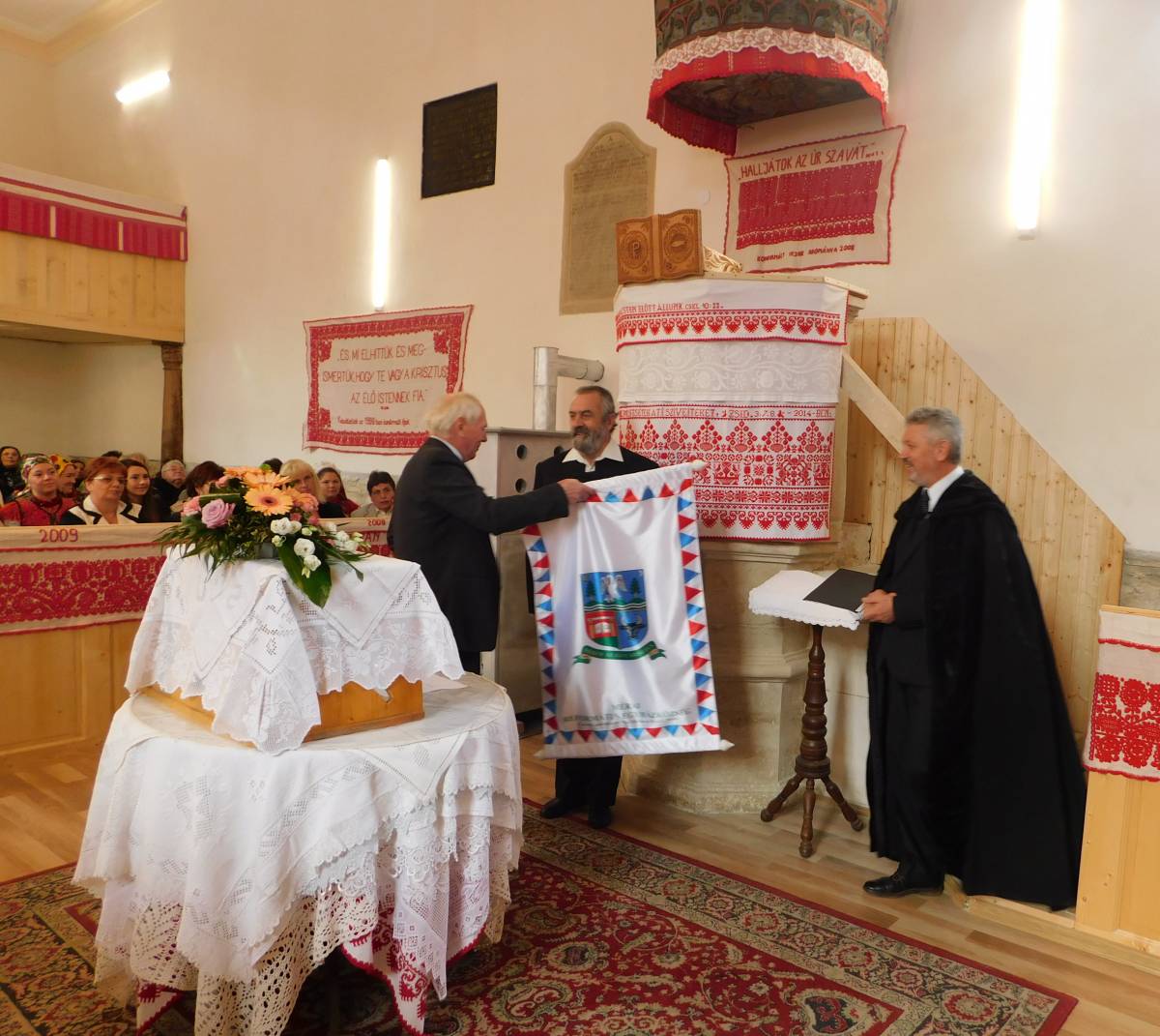 Dési Zoltán főgondnok, Pécsi L. Dániel jelképtervező és Mezei Csaba helyi református lelkész az új gyülekezeti zászló és címer felavatásán • Fotó: Okos Márton