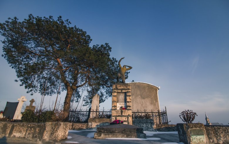 Az Égbenéző – a Fekete család síremléke, háttérben a katolikus templommal •  Fotó: Sütő Éva