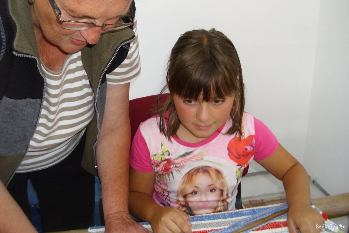 Évi néni türelmesen magyarázza, hogyan lesz a rongyból szőnyeg •  Fotó: Tamás Gyopár