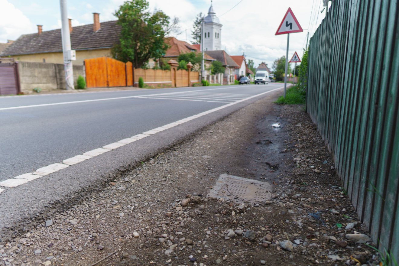 A főút mentén van a problémás akna, így az autók felspriccolják a szennyvizet •  Fotó: Tuchiluș Alex