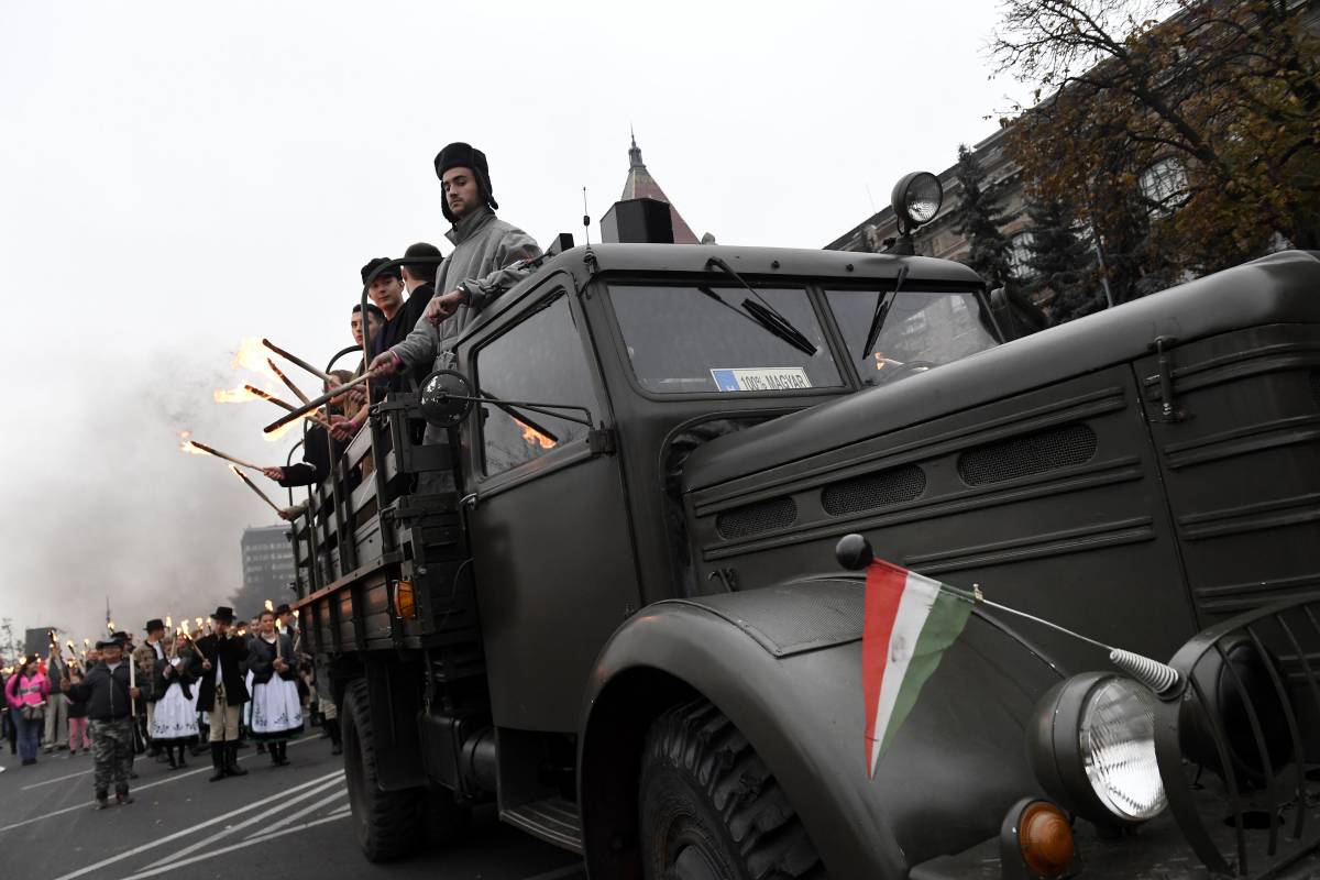 Korhű ruhába öltözött fiatalok egy Csepel teherautó platóján a Bem térre tartó hagyományos fáklyás emlékmeneten &bullet;  Fotó: MTI