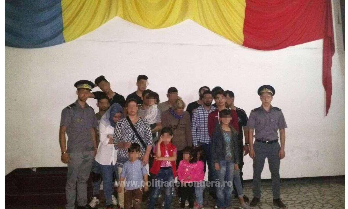 Határőrök csoportképe a migránsokkal a román zászló alatt 