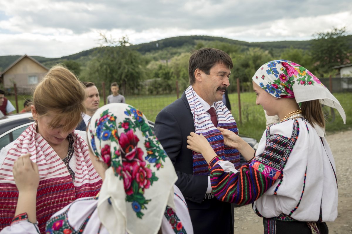 Áder János köztársasági elnök és felesége, Herczegh Anita nyakába „kendezőt” adnak a Bákó megyei Lészpeden •  Fotó: MTI/Mohai Balázs