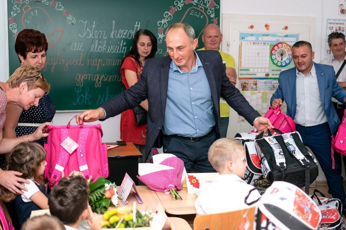 Bizakodók. Décsei Attila megyei RMDSZ-elnök és Antal Attila aligazgató iskolatáskákat osztogat az előkészítősöknek a tanévnyitón &bullet;  Fotó: Facebook / RMDSZ Beszterce-Naszód