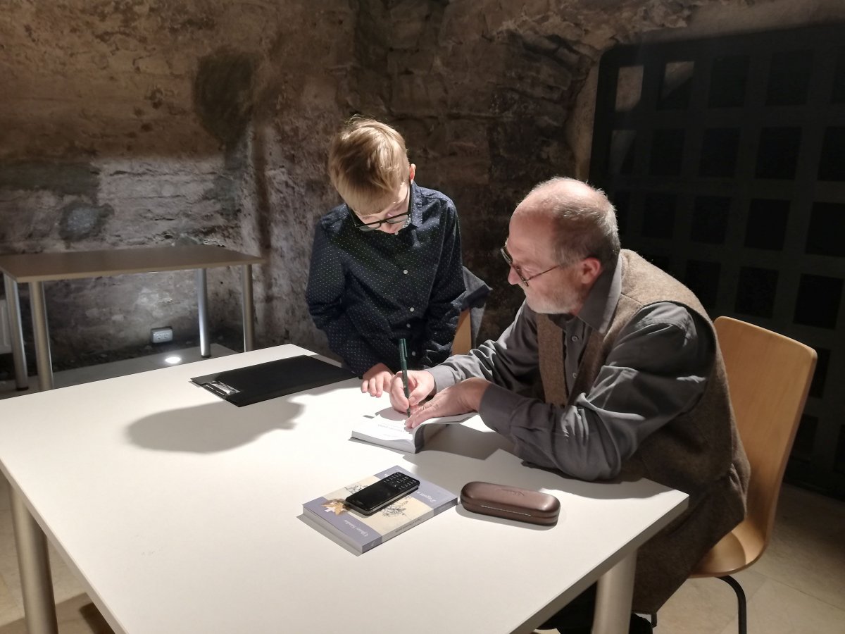 Benkő Levente dedikálja a kötetet az őt faggató 5. osztályos Püsök Andrisnak •  Fotó: Pap Melinda