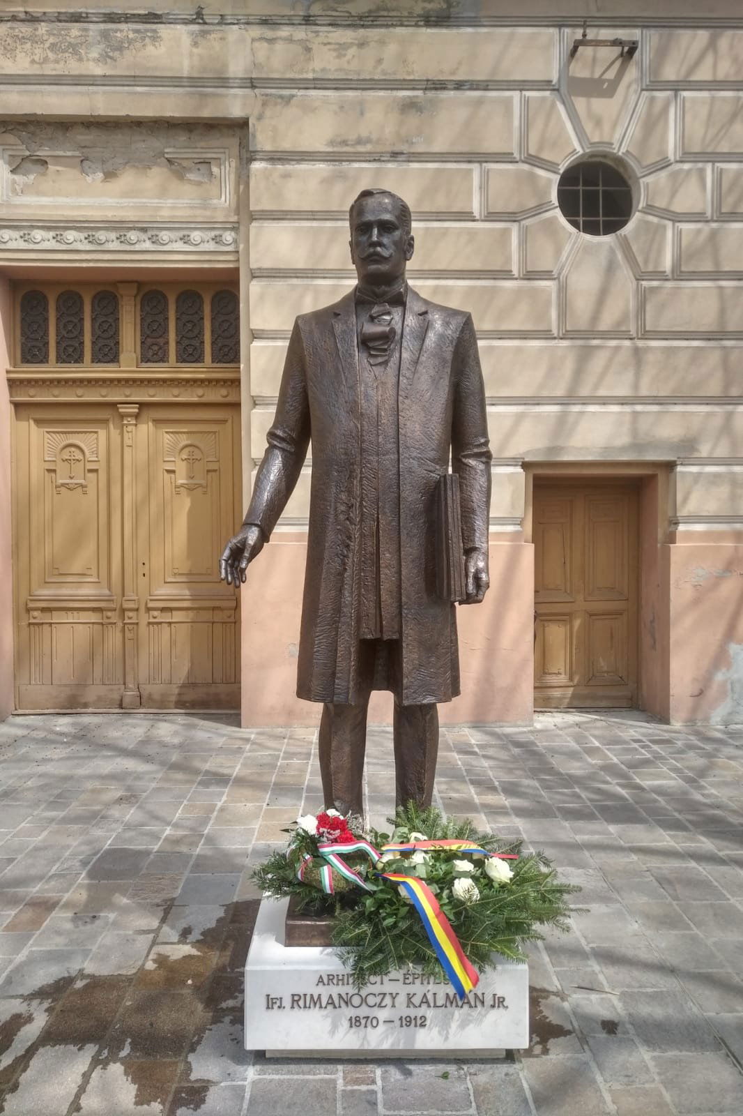 Normalitás. Román és magyar felirat, román és magyar szalagos koszorú ifj. Rimanóczy Kálmán szobrának talapzatán &bullet;  Fotó: Ilie Bolojan/Facebook