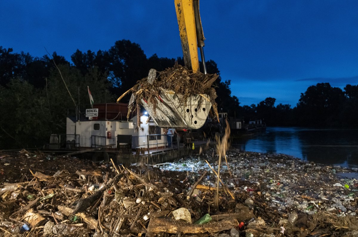 Munkagép kiemeli a Szamos áradásával Romániából érkezett kommunális hulladékot és természetes uszadékot a folyó partján kialakított kármentesítő helyen a magyarországi Olcsván •  Fotó: MTI/Balázs Attila