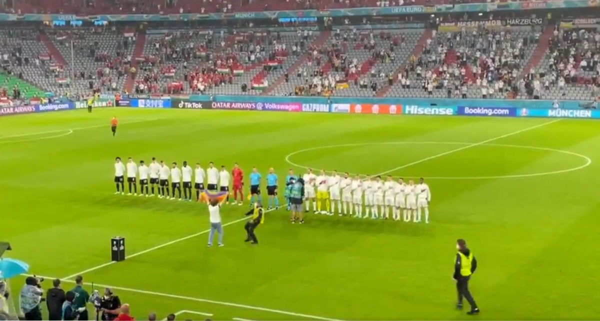 Szivárványos zászlóval fut be egy szurkoló a Münchenben játszott német–magyar Eb-meccs előtt, a magyar himnusz alatt &bullet;  Fotó: Videófelvétel