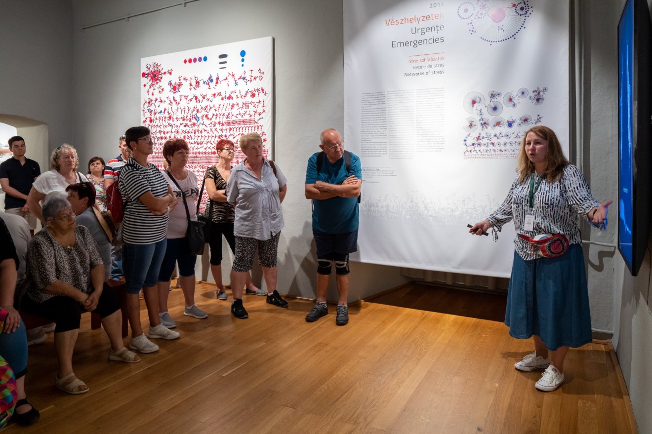 Hompoth Hanna-Erika tárlatvezető muzeológus (jobbra) ismerteti meg a közönséggel a Rejtett mintázatok című kiállítást •  Fotó: Csíki Székely Múzeum/ Gegő Imre