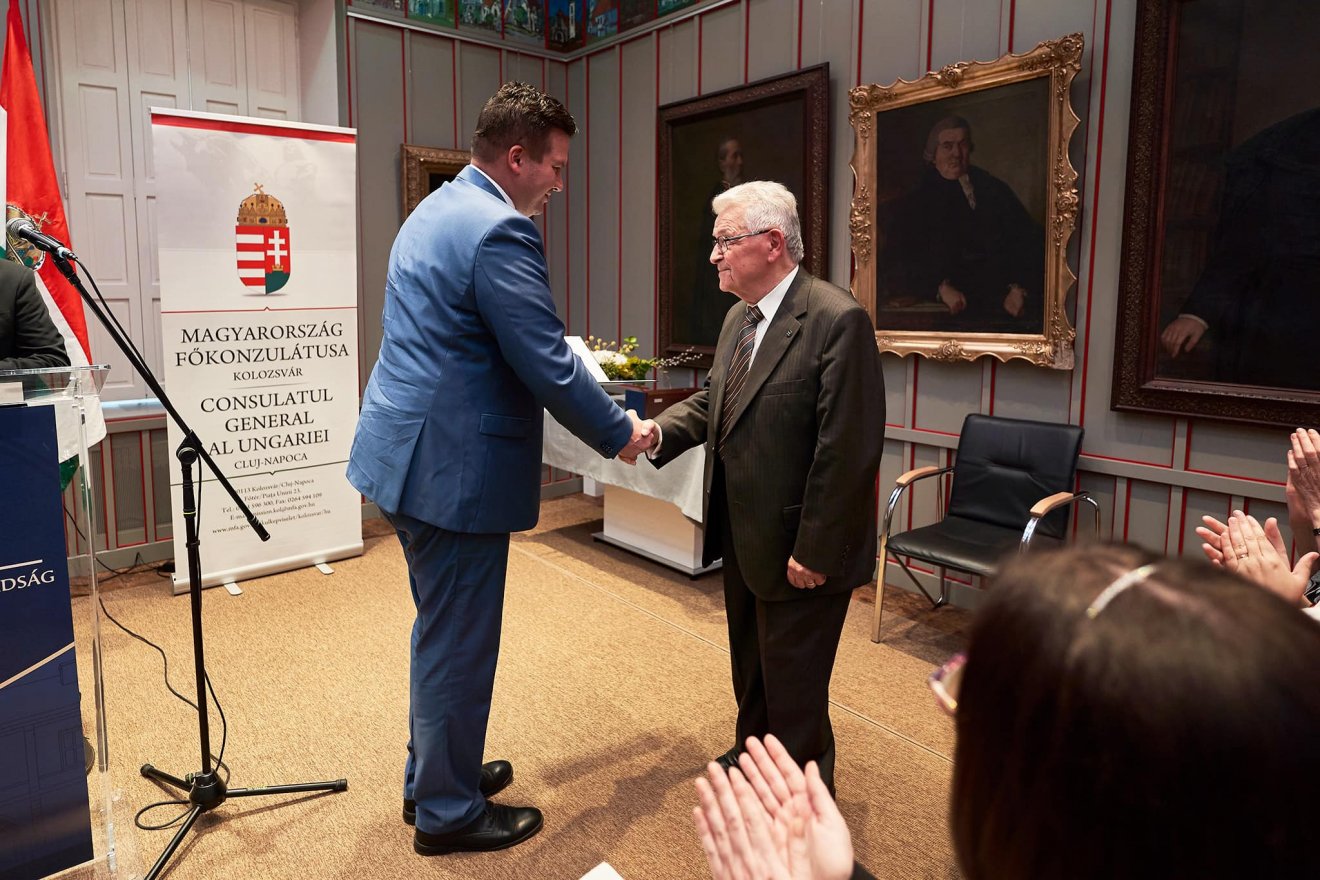 Grezsa Csaba kolozsvári főkonzul (balra) átadja Péntek János nyelvésznek, professor emeritusnak a Novák Katalin köztársasági elnök által adományozott Széchenyí-díjat •  Fotó: Magyarország Kolozsvári Főkonzulátusa