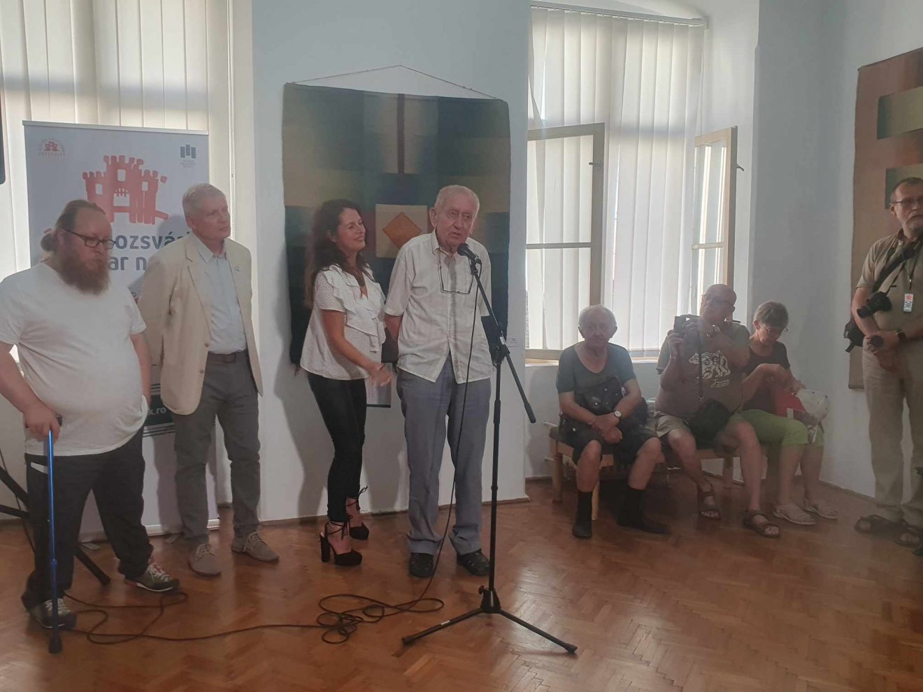Gazda József kovásznai közíró, a kiállítás kurátora, Gazdáné Olosz Ella textilművész férje is beszélt az életműről a tárlatmegnyitón, mellette balról a második Szücs György, a budapesti Magyar Nemzeti Galéria főigazgató-helyettese •  Fotó: Kiss Judit