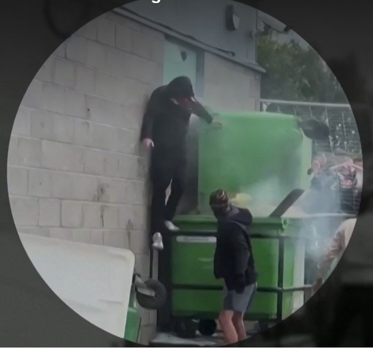 Thomas Birley (fenn) a felgyújtott szemeteskukákat igazítja •  Fotó: Videófelvétel/Nagy-britanniai rendőrség