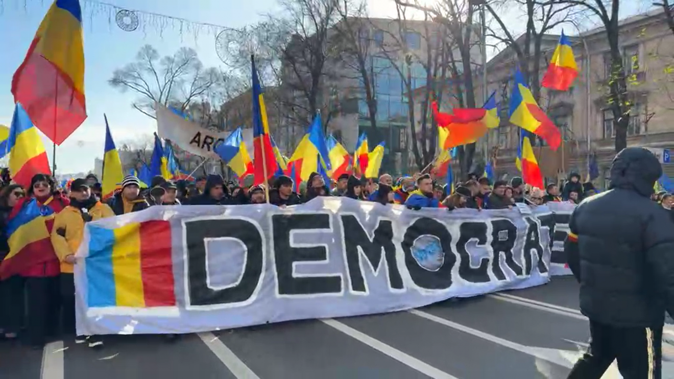 Utcára vonultak az AUR-szimpatizánsai. Az első sorban állók egy „Demokrácia” feliratú óriásmolinót tartanak a kezükben, amelyen a román trikolór és egy VOTAT feliratú pecsét is látható