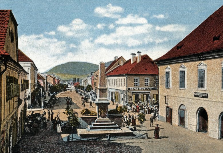 Az 1897-ben felavatott millenniumi emlékoszlop az első világháború előtt, háttérben a Kossuth Lajos utca •  Fotó: korabeli képeslap, forrás: Civilek az Örökségért Mozgalom