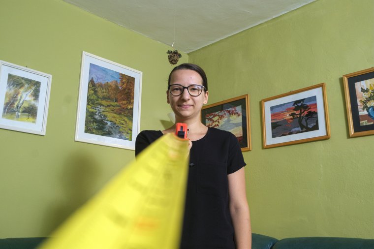 Lézermérő és mérőszalag egy fiatal lány kezében