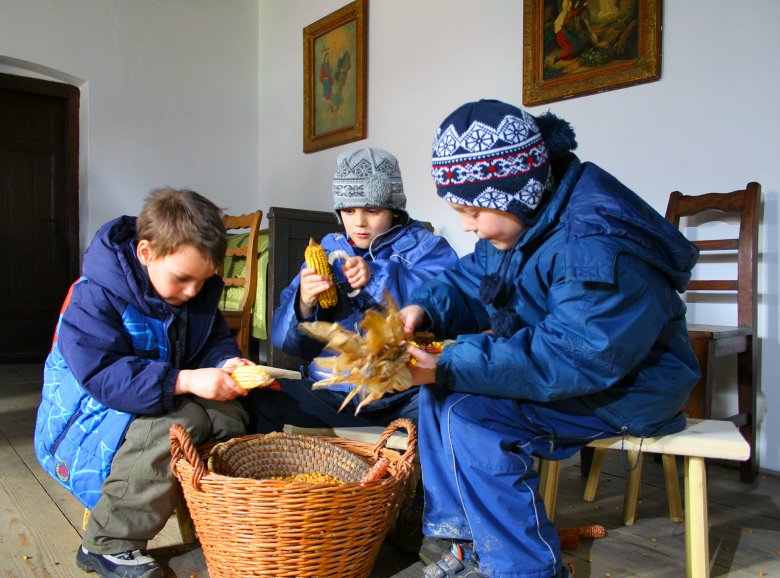 Kukoricát morzsoló gyerekek a skanzenben. Emlékezetes élmények •  Fotó: Skanzen – Szabadtéri Néprajzi Múzeum